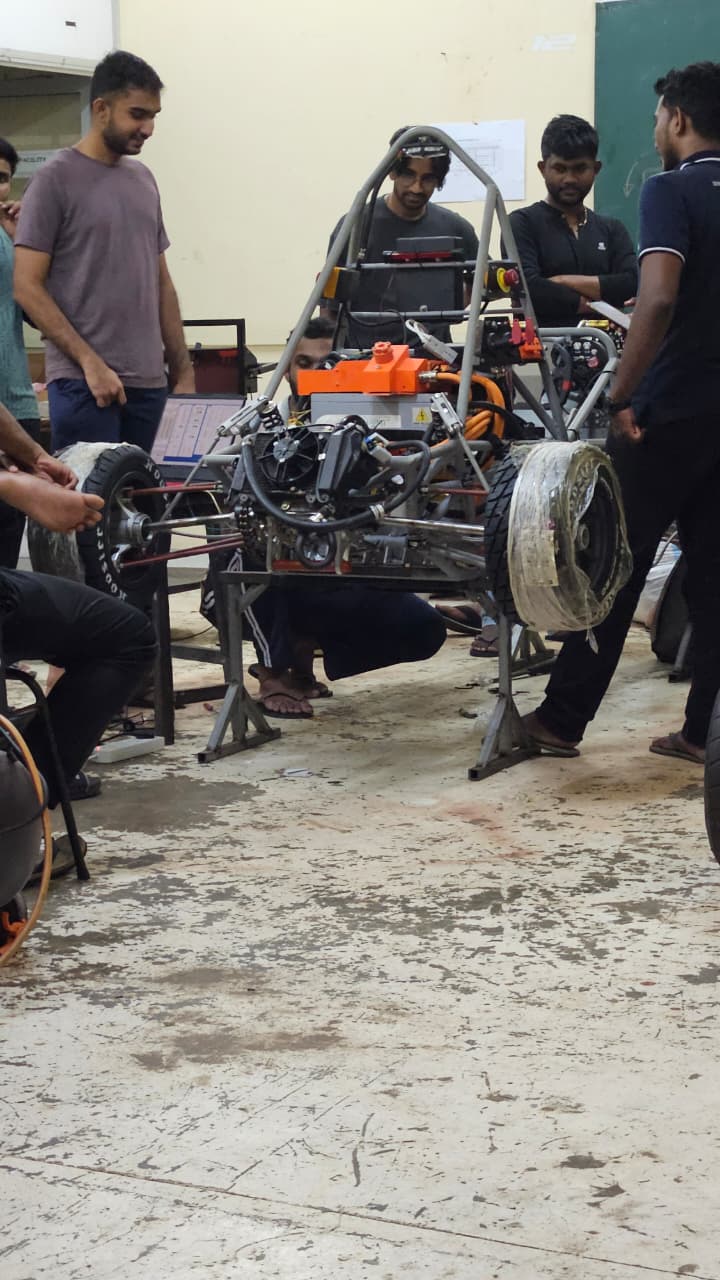 Team members working around the prototype electric race car during assembly